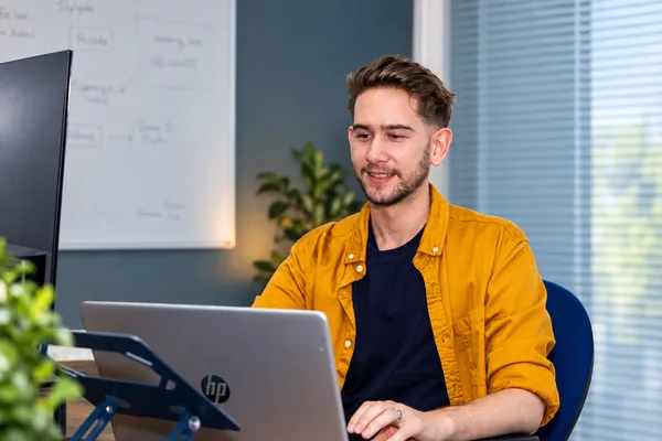 A Double Glazing Leads team member in a yellow shirt working at a laptop
